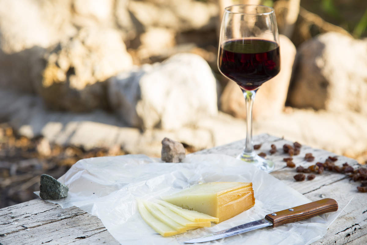 Pieces of cheese and raisins with a red wine glass